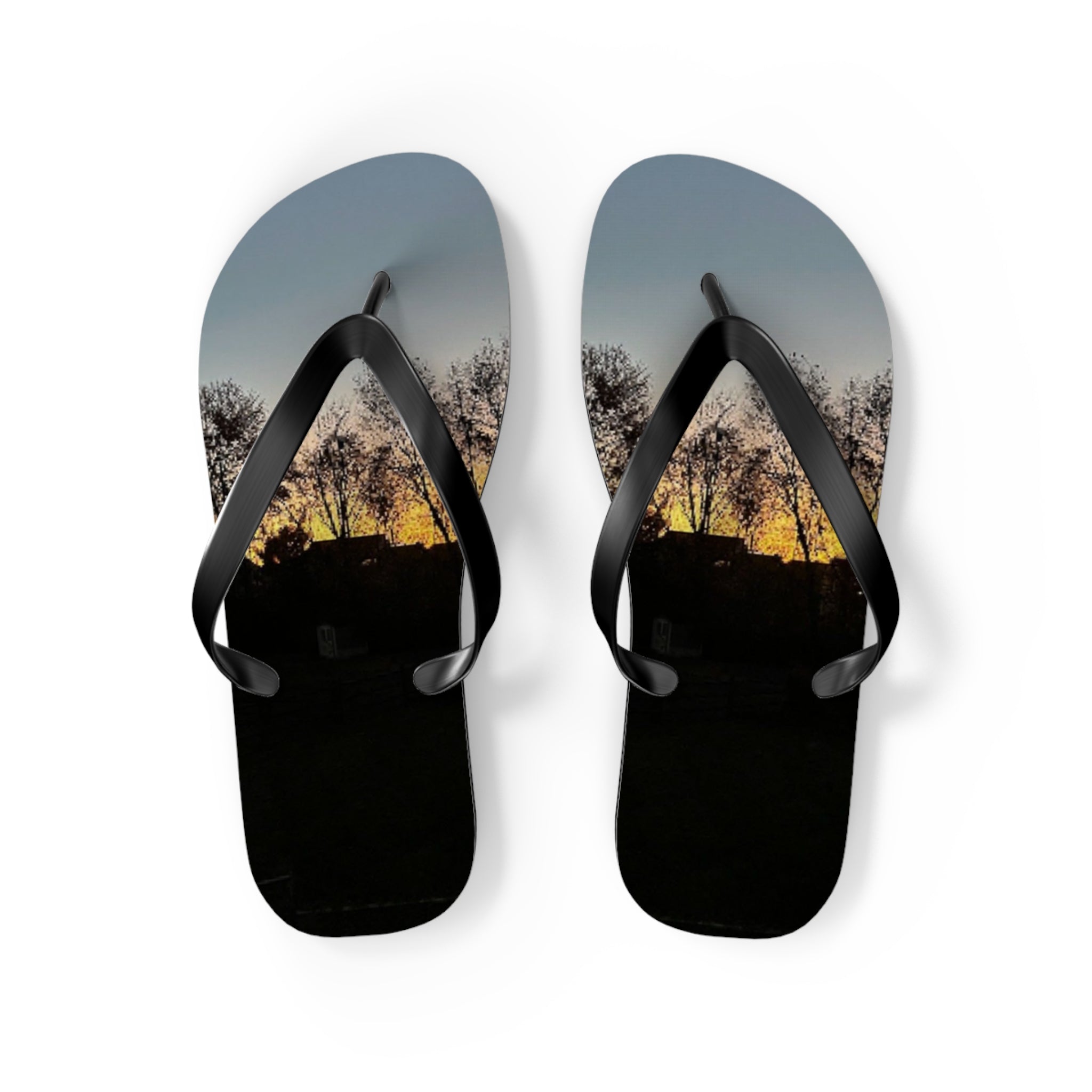 Black flip-flops with a sunset and silhouetted trees scene.