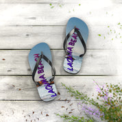 Laguna Beach flip flops on weathered wood with flowers and sand.