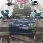 River scene table runner with pink flowers and blue dishes.