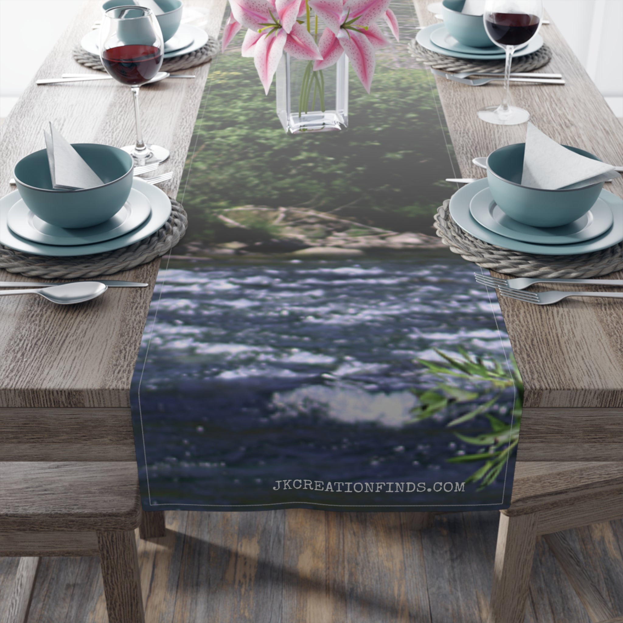 River scene table runner with pink flowers and blue dishes.
