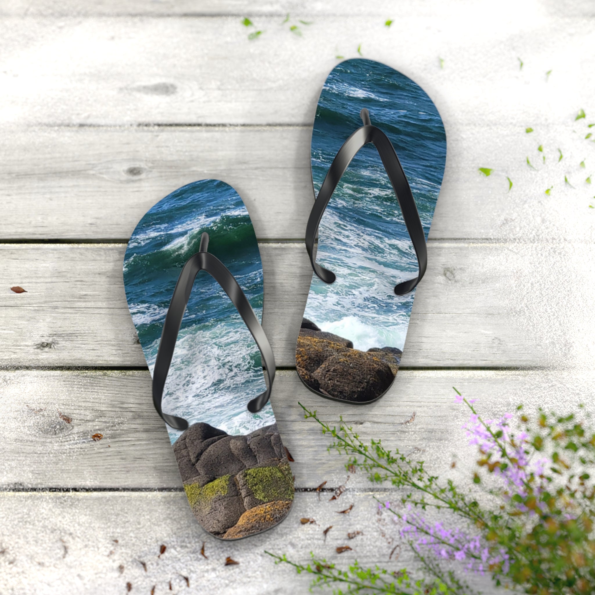 Flip-flops with an ocean wave and rocky shore design on a wooden surface.