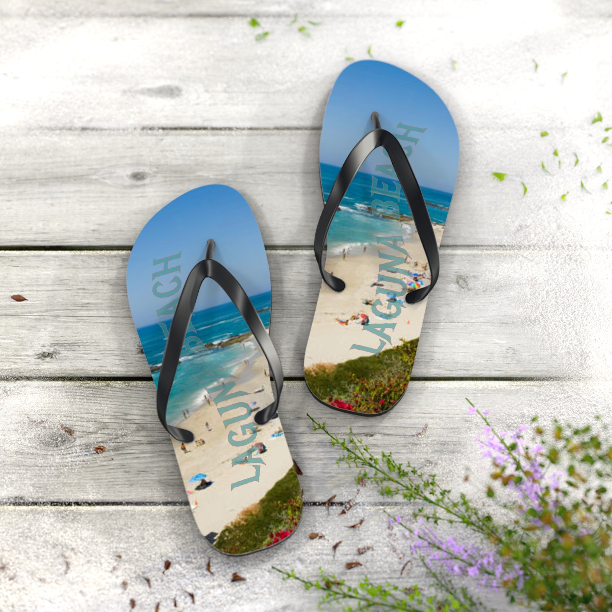 Laguna Beach flip-flops on a wooden surface with flowers.