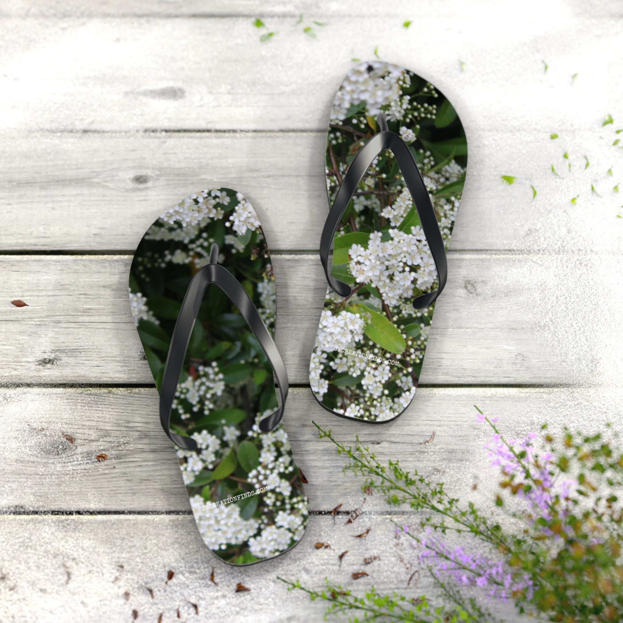 Flip-flops with white flowers on a wooden deck.