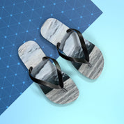 Black flip-flops with marble print on a light blue and patterned background.