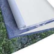 Rolled fabric sample with blurred landscape print and white backing.