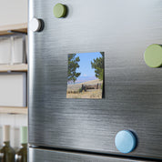 Stone building with trees and mountains in background on refrigerator magnet.