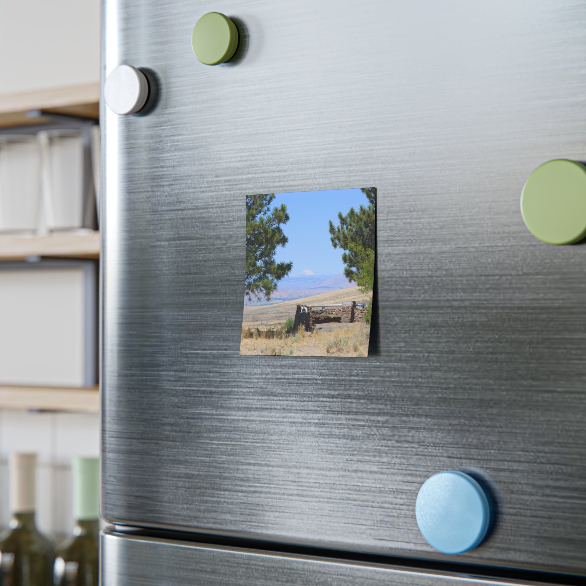 Stone building with trees and mountains in background on refrigerator magnet.