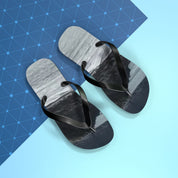 Black flip-flops with a rocky landscape design on a blue and white background.