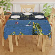 Tablecloth with windsurfers on a lake, set on a wooden table.
