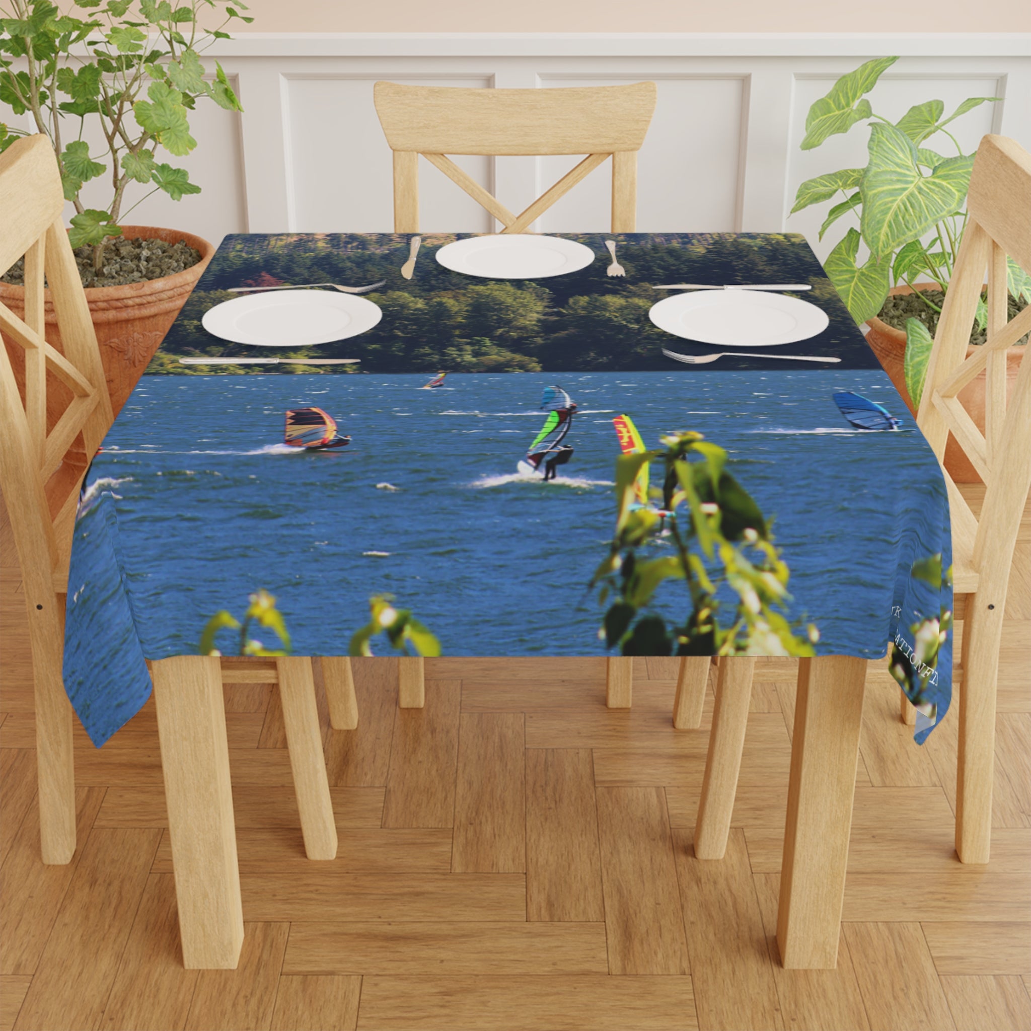 Tablecloth with windsurfers on a lake, set on a wooden table.