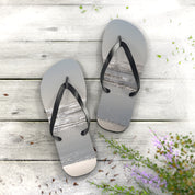 Flip-flops with a beach scene on the soles, resting on a wooden surface.
