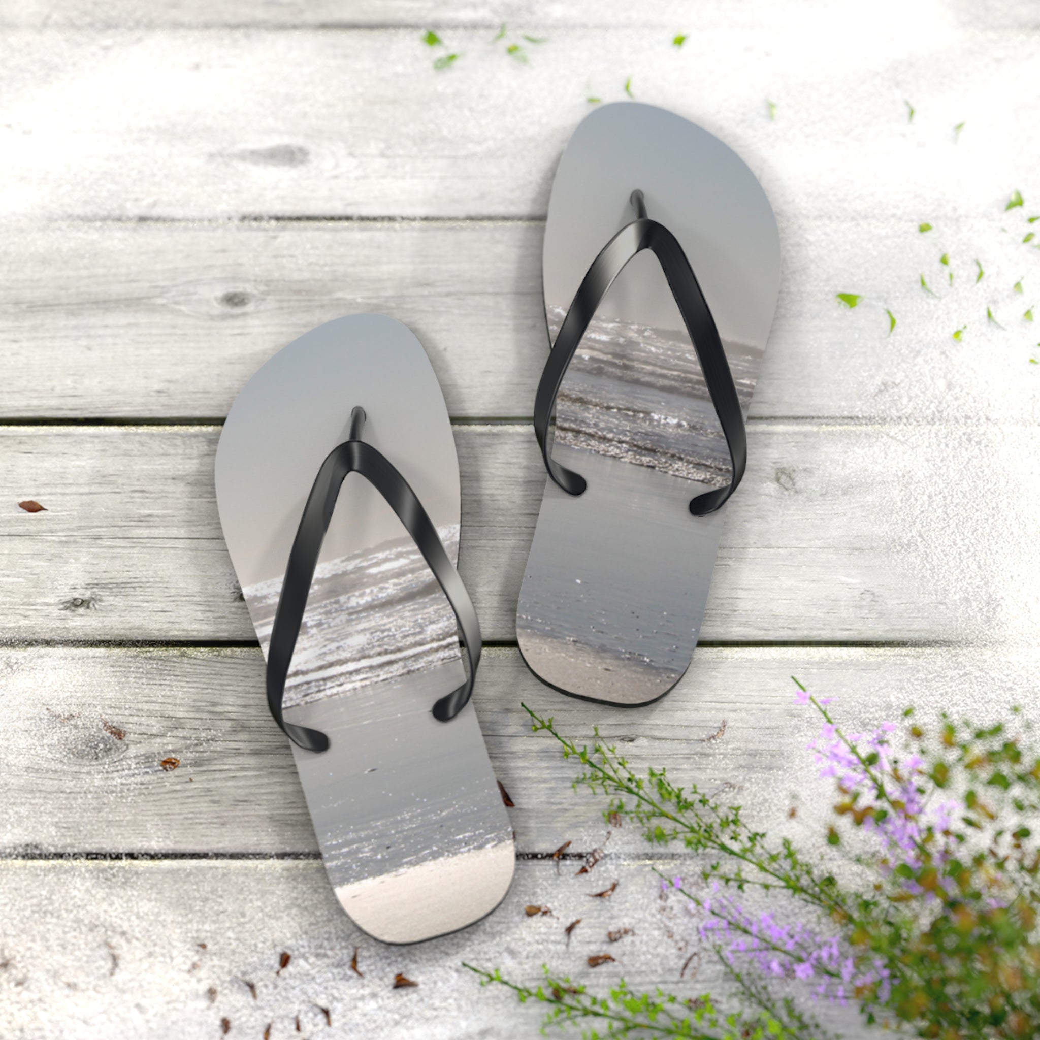 Flip-flops with a beach scene on the soles, resting on a wooden surface.