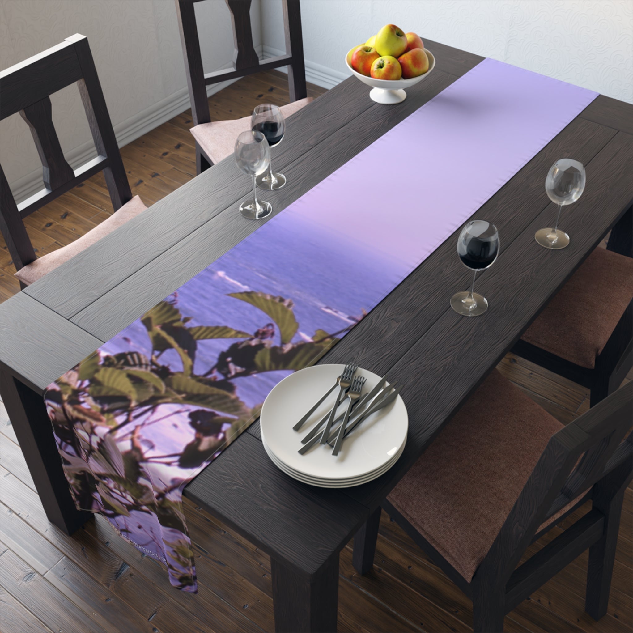 Table runner with lavender print on a dining table with plates and glasses.