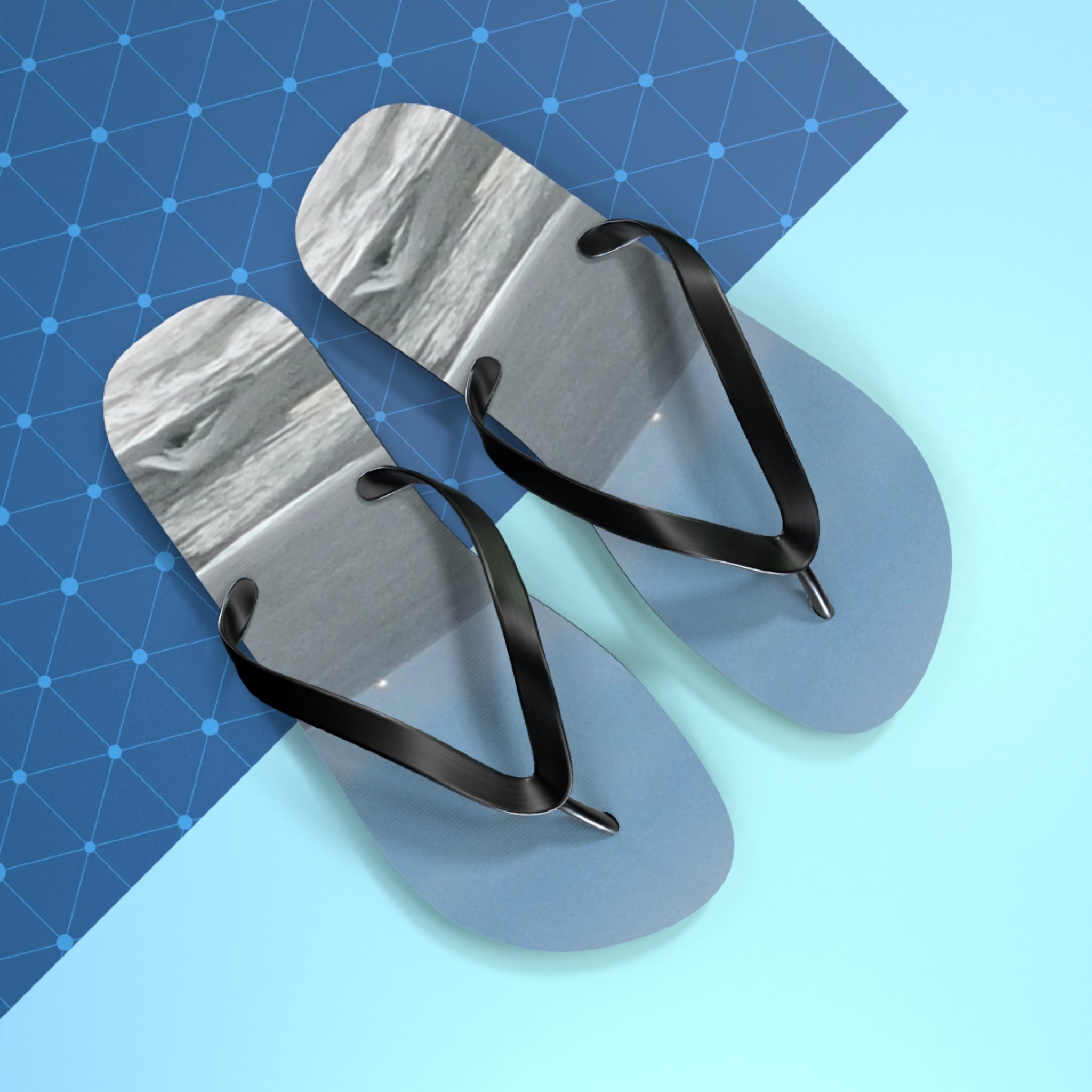 Light blue flip-flops with black straps on a blue grid background.