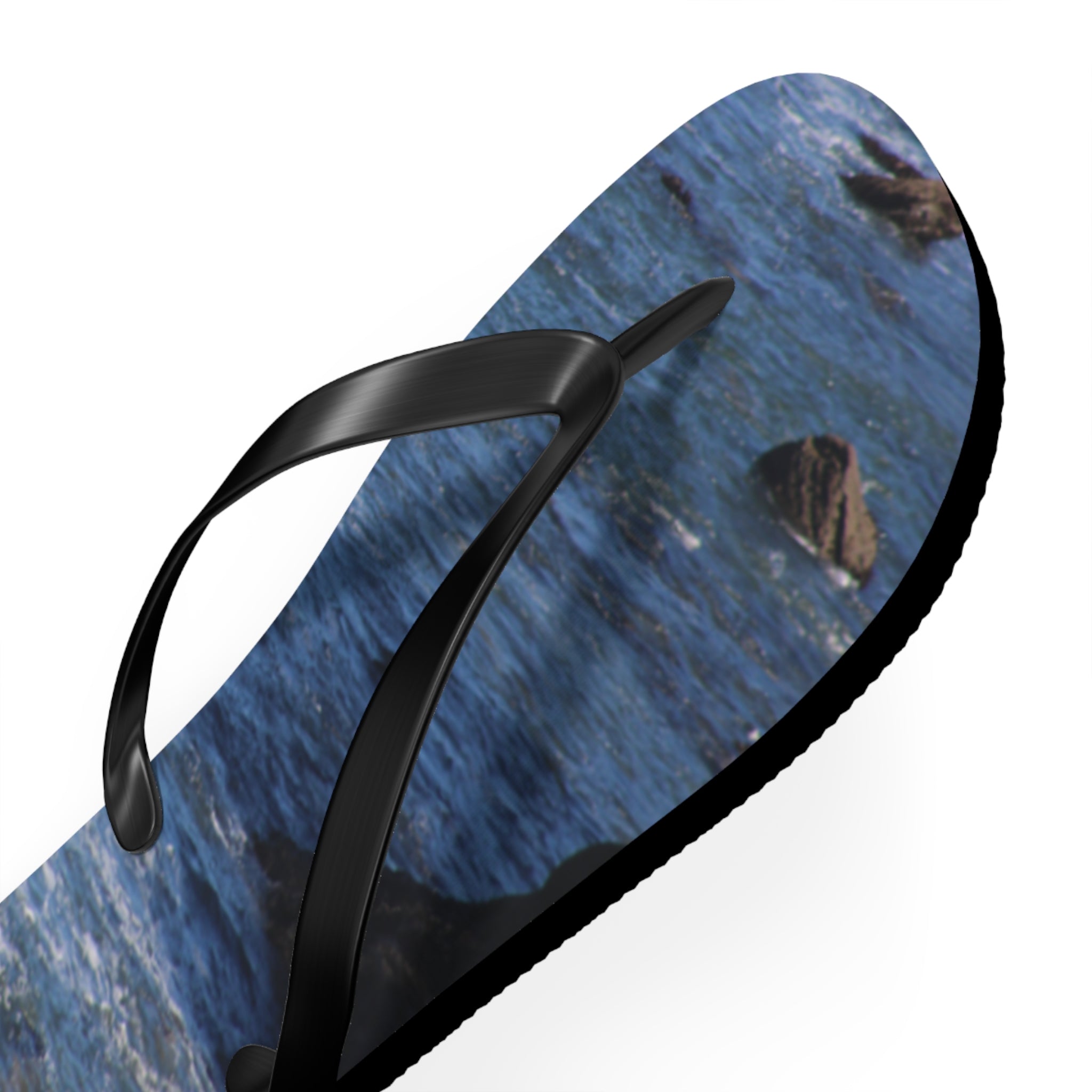 Black flip-flop with a blue ocean and rock pattern.