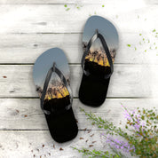 Flip-flops with a sunset landscape scene on a wooden deck.