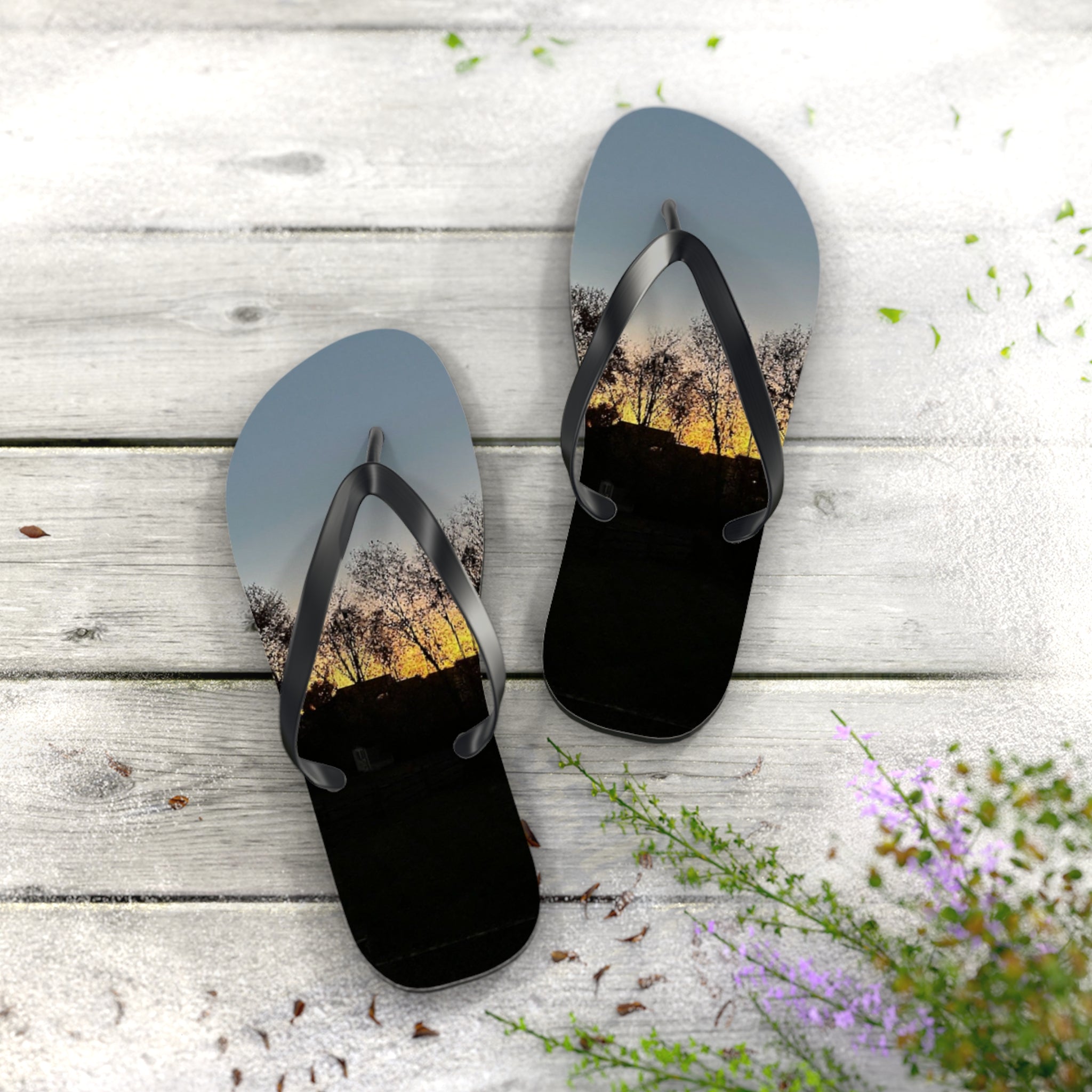Flip-flops with a sunset landscape scene on a wooden deck.