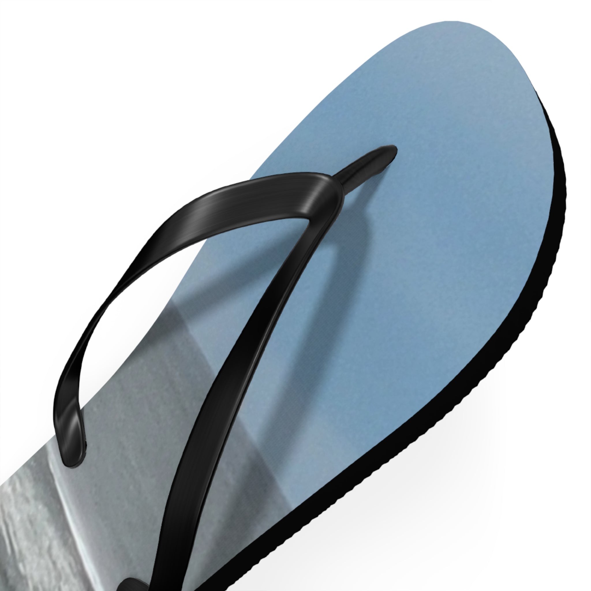 Black flip-flop with blue sole, showing a beach scene.
