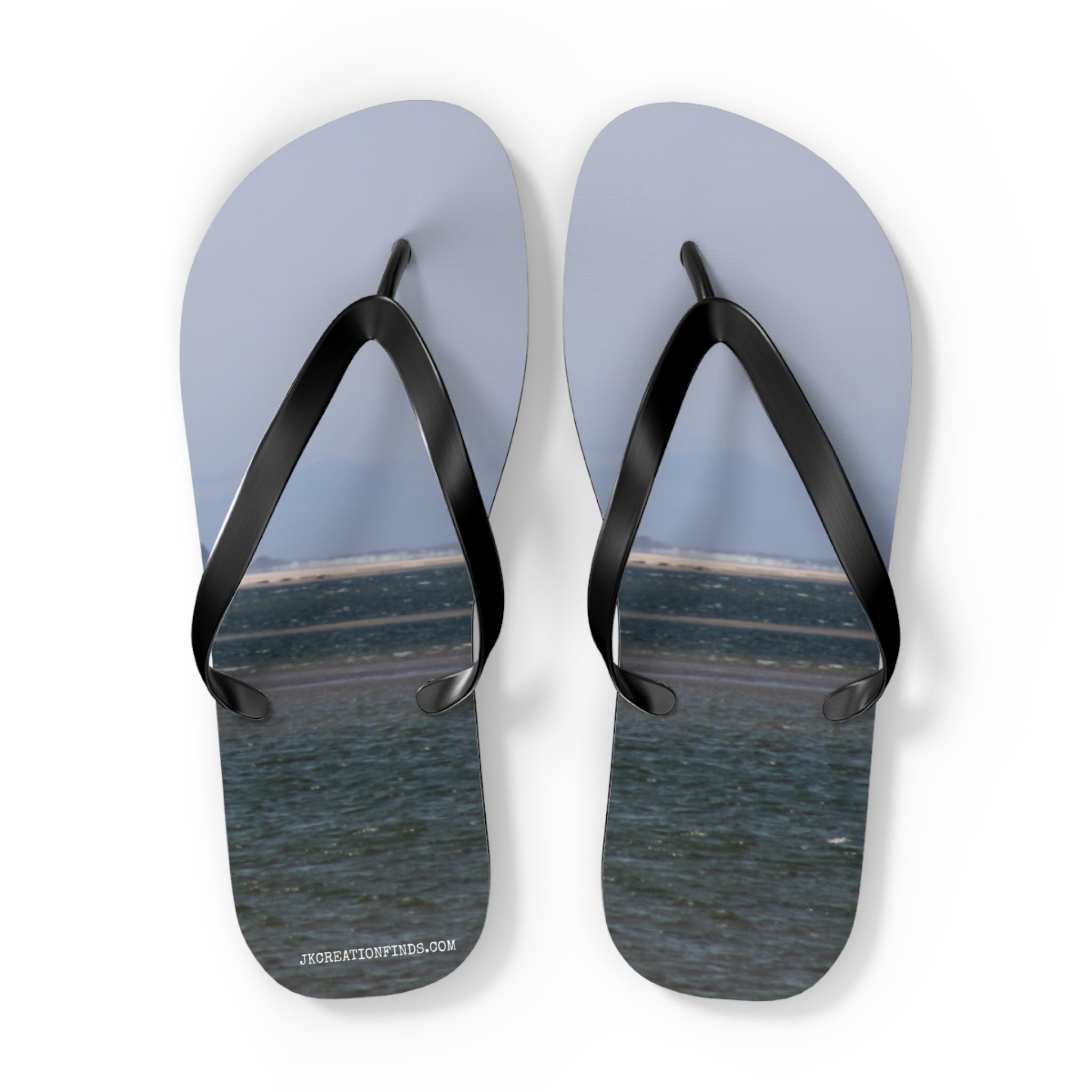Flip flops with a beach and ocean scene printed on the soles.