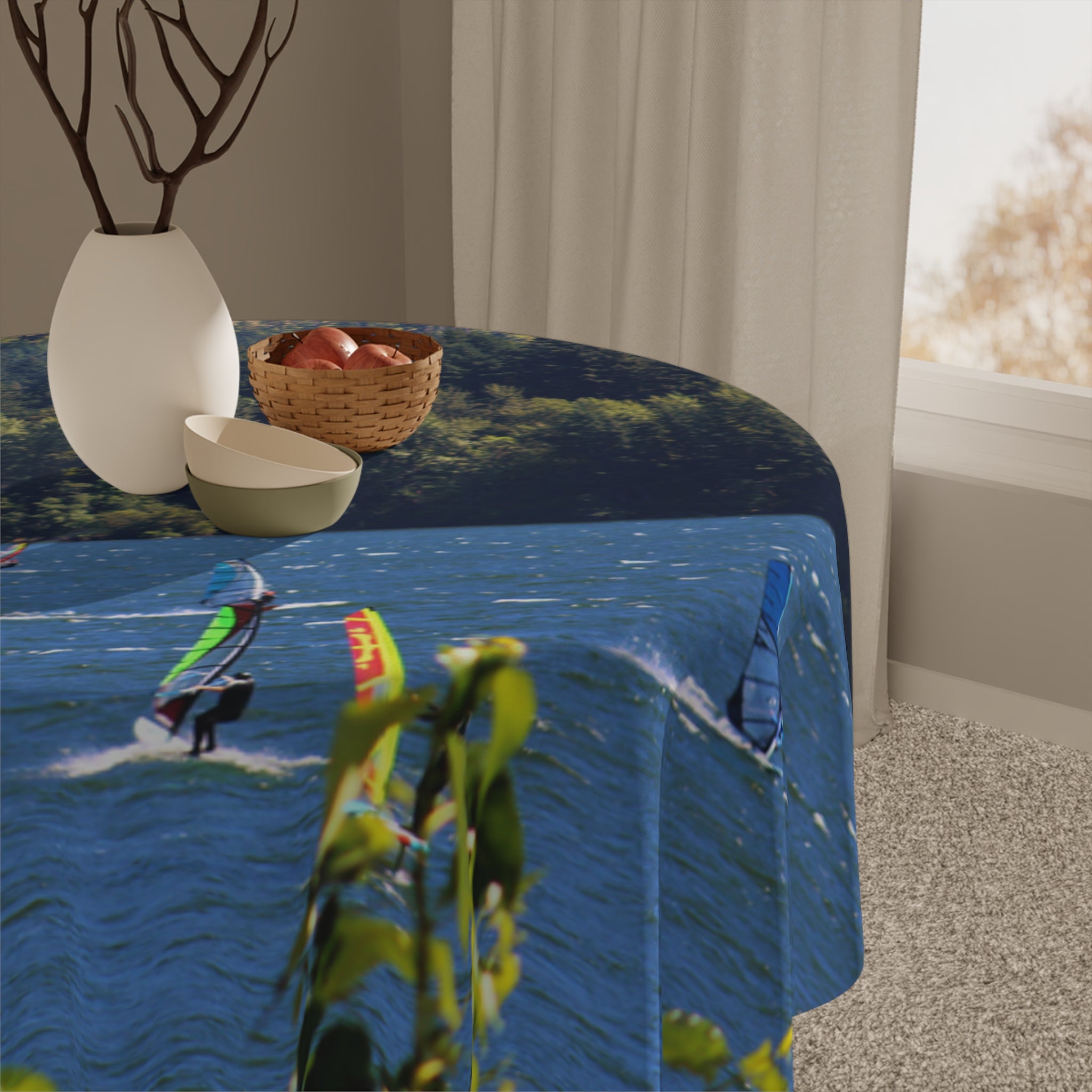 Round tablecloth with windsurfers on blue water and green foliage.