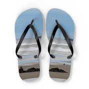 Flip-flops with beach scene showing two small figures and ocean waves.