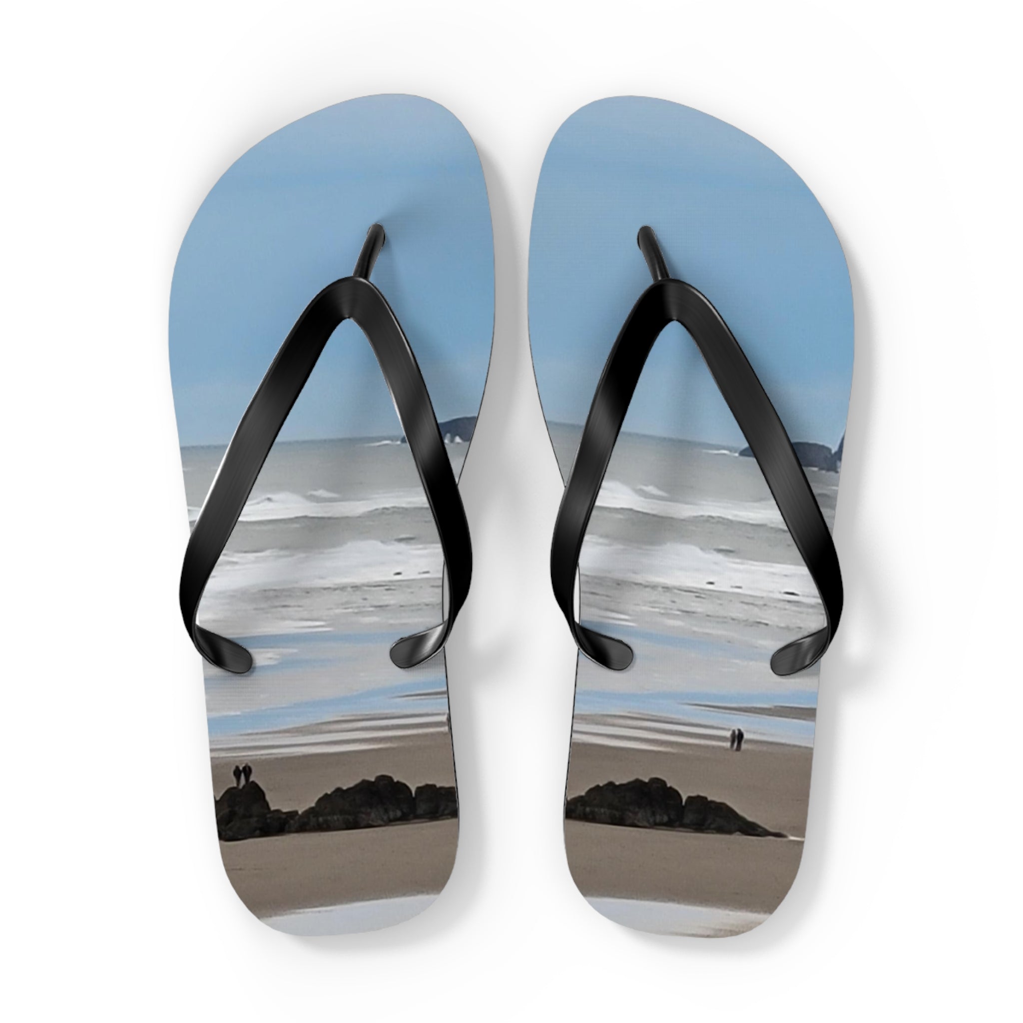 Flip-flops with beach scene showing two small figures and ocean waves.