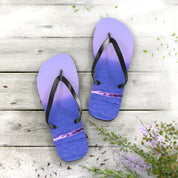 Purple flip-flops with ocean wave print on a wooden surface.