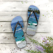 Flip-flops with ocean and beach scene on a wooden deck.