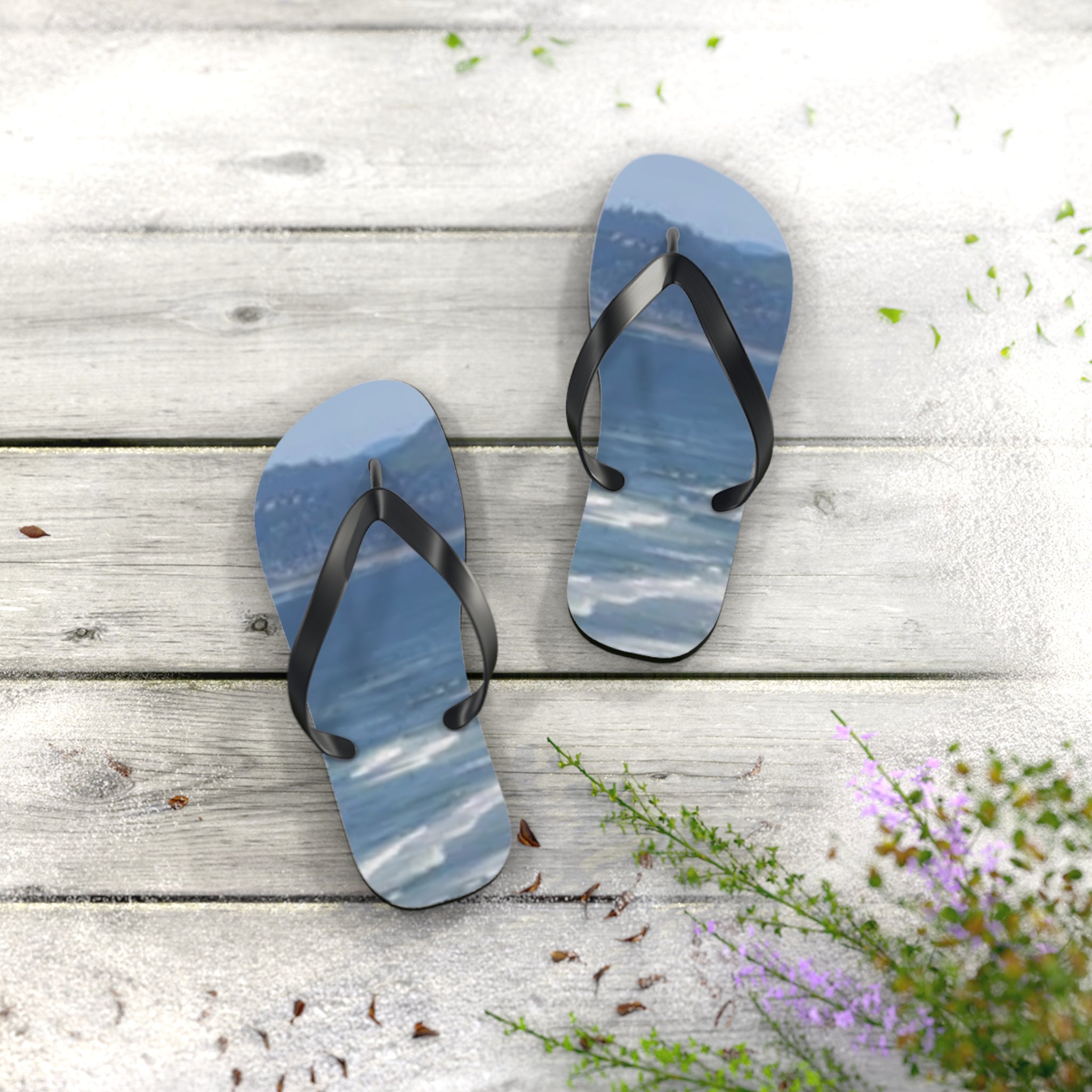Flip-flops with a beach and ocean scene printed on the soles, resting on a wooden surface.