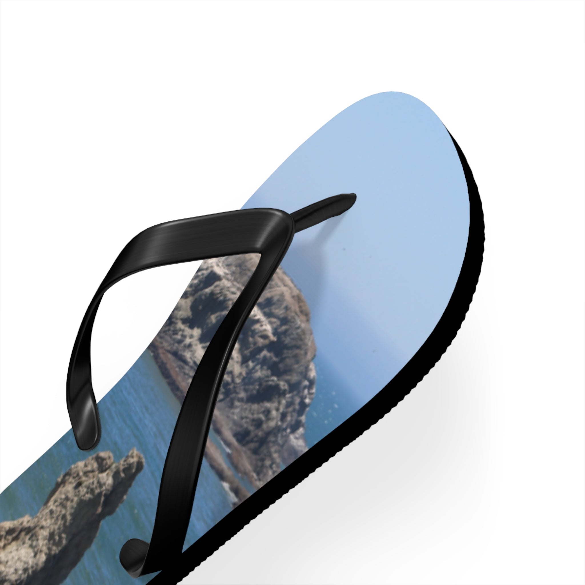 Flip-flops with a scenic coastal landscape on the straps and soles.