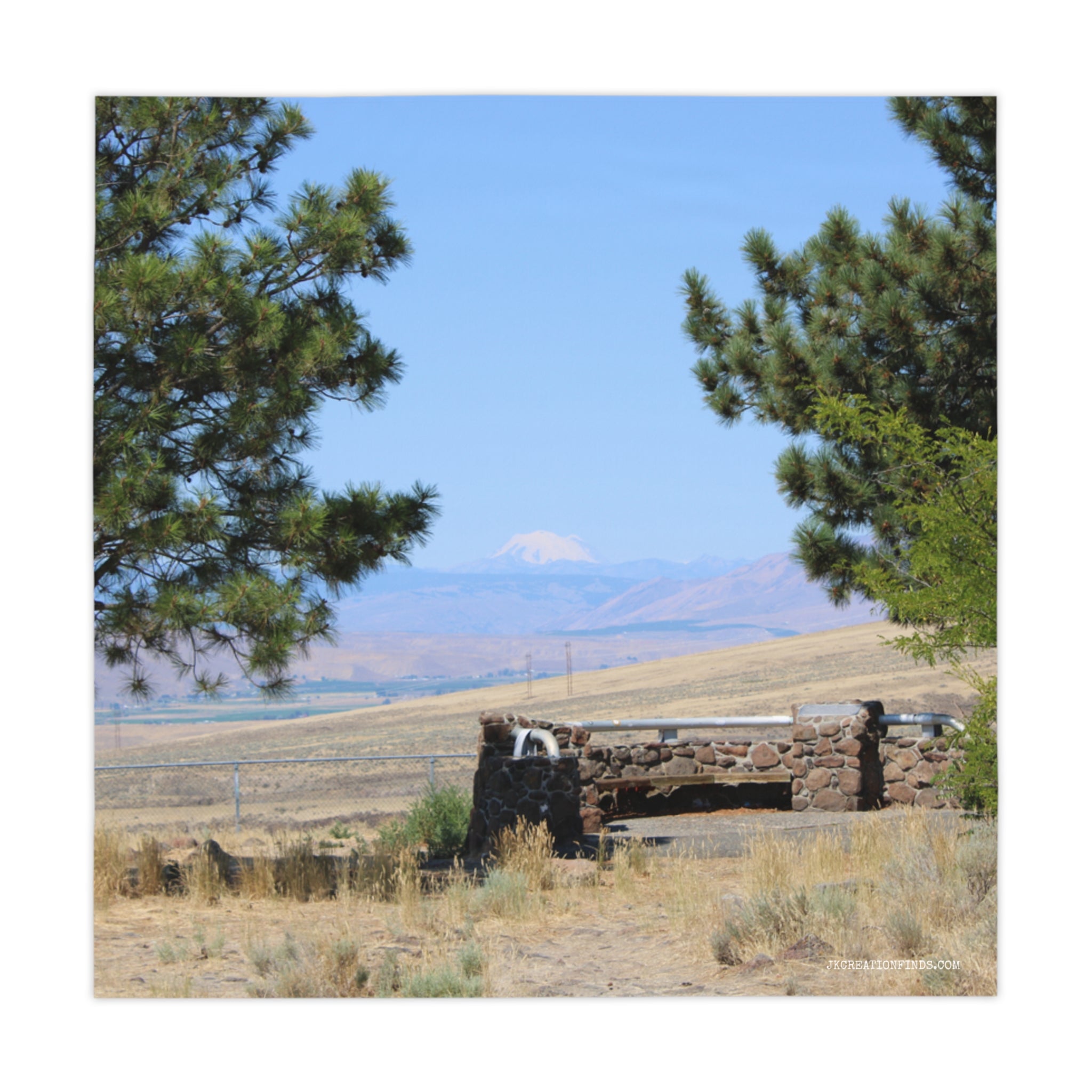 Stone structure with water fountain, framed by pine trees, with distant mountain.