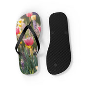 Flip-flops with pink tulips and purple flowers on a sunny day.