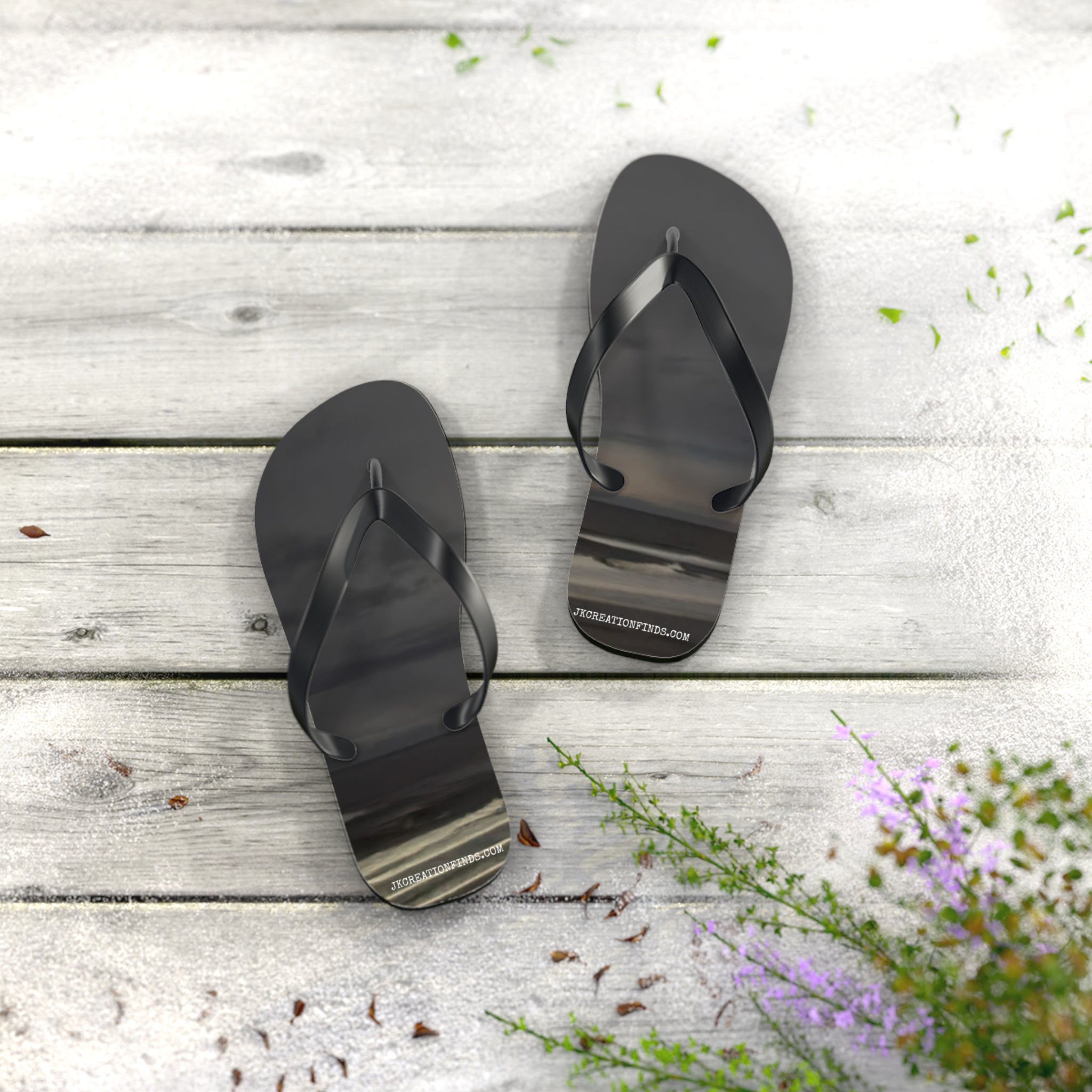 Black flip-flops with beach scene reflections on weathered wooden planks.