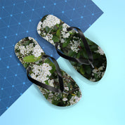 Flip-flops with white flowers and green leaves pattern on blue background.