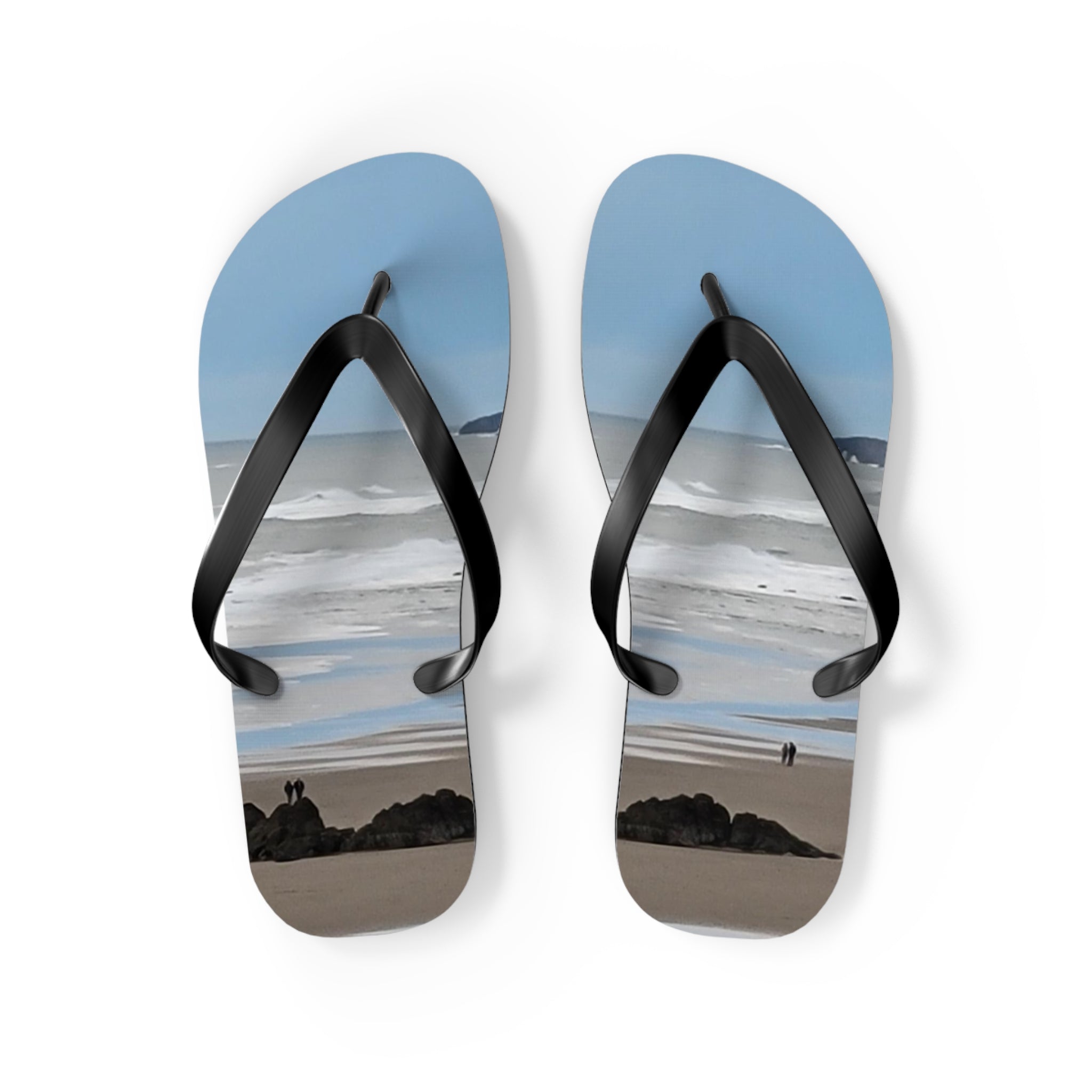Flip-flops with a beach scene featuring two figures and ocean waves.