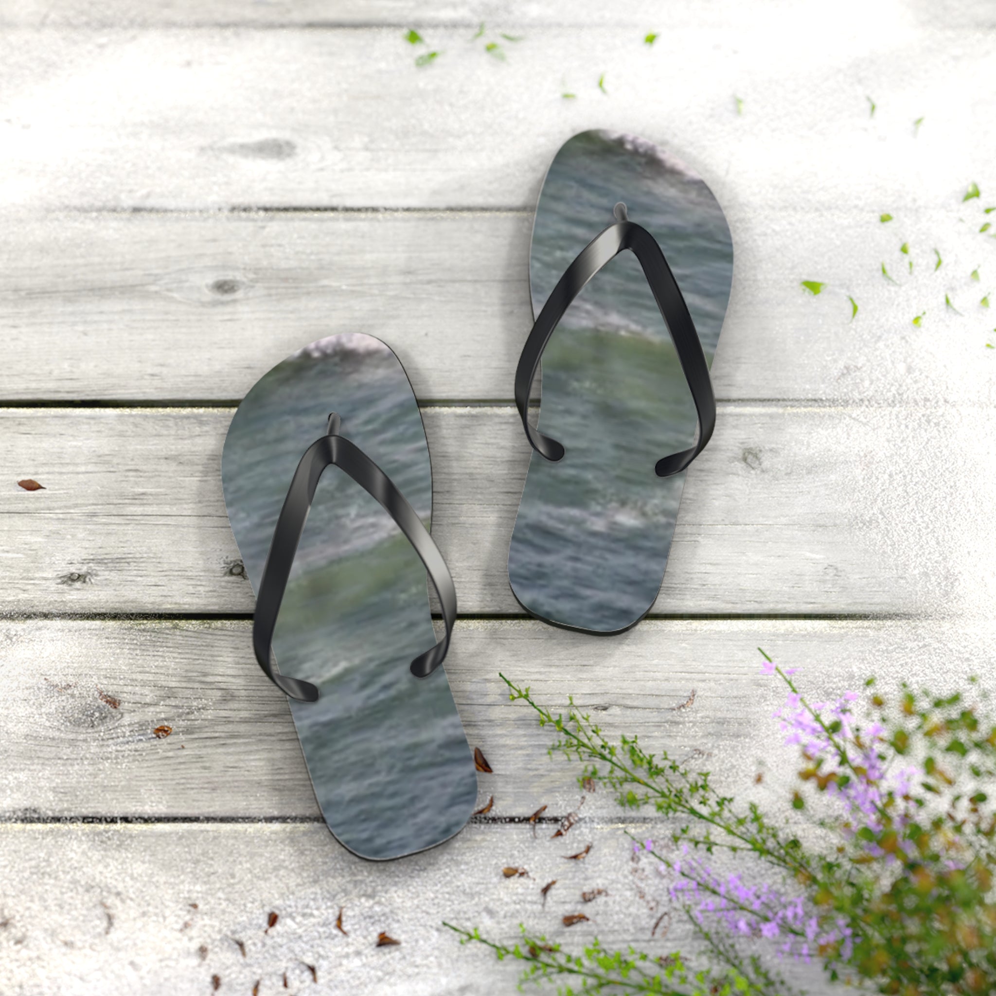 Flip-flops with ocean wave pattern on a wooden surface with purple flowers.