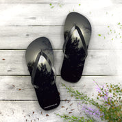 Black flip-flops with tree reflections on a weathered wooden surface.