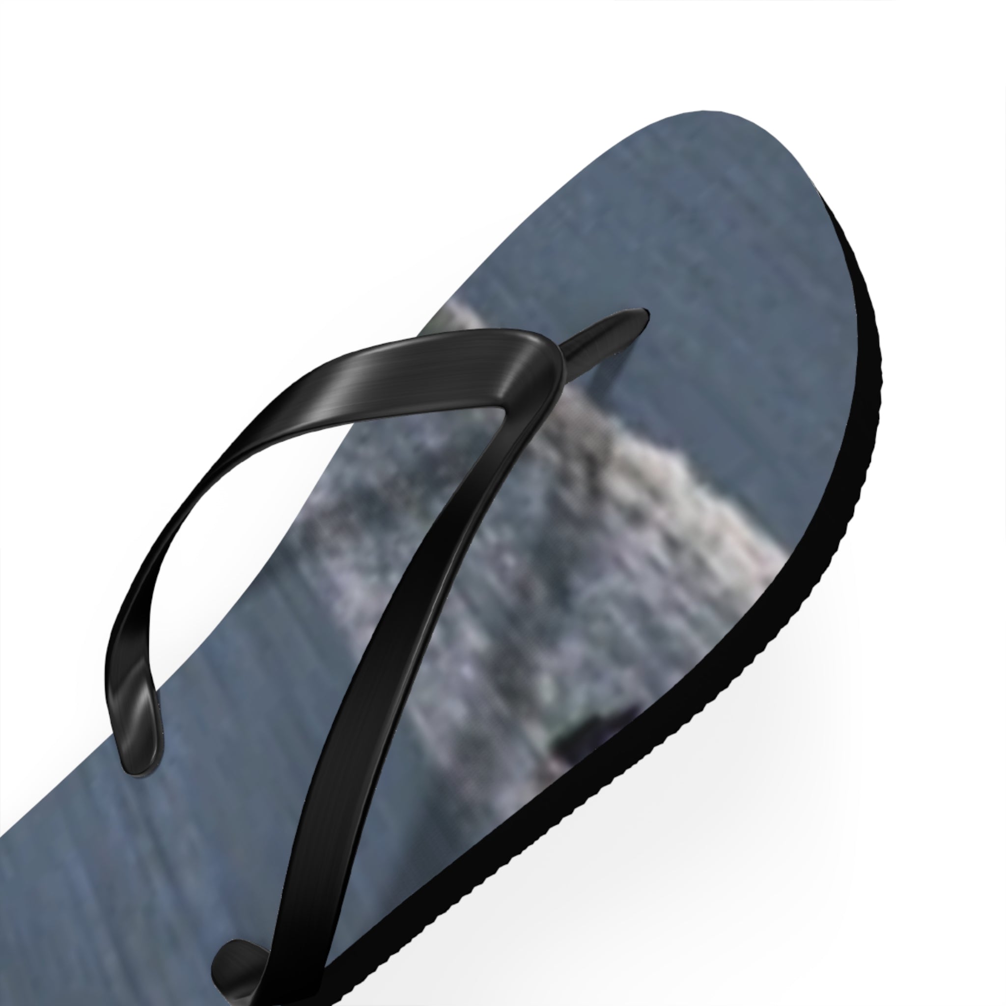 Black strap flip-flop with textured blue sole featuring a blurred landscape.