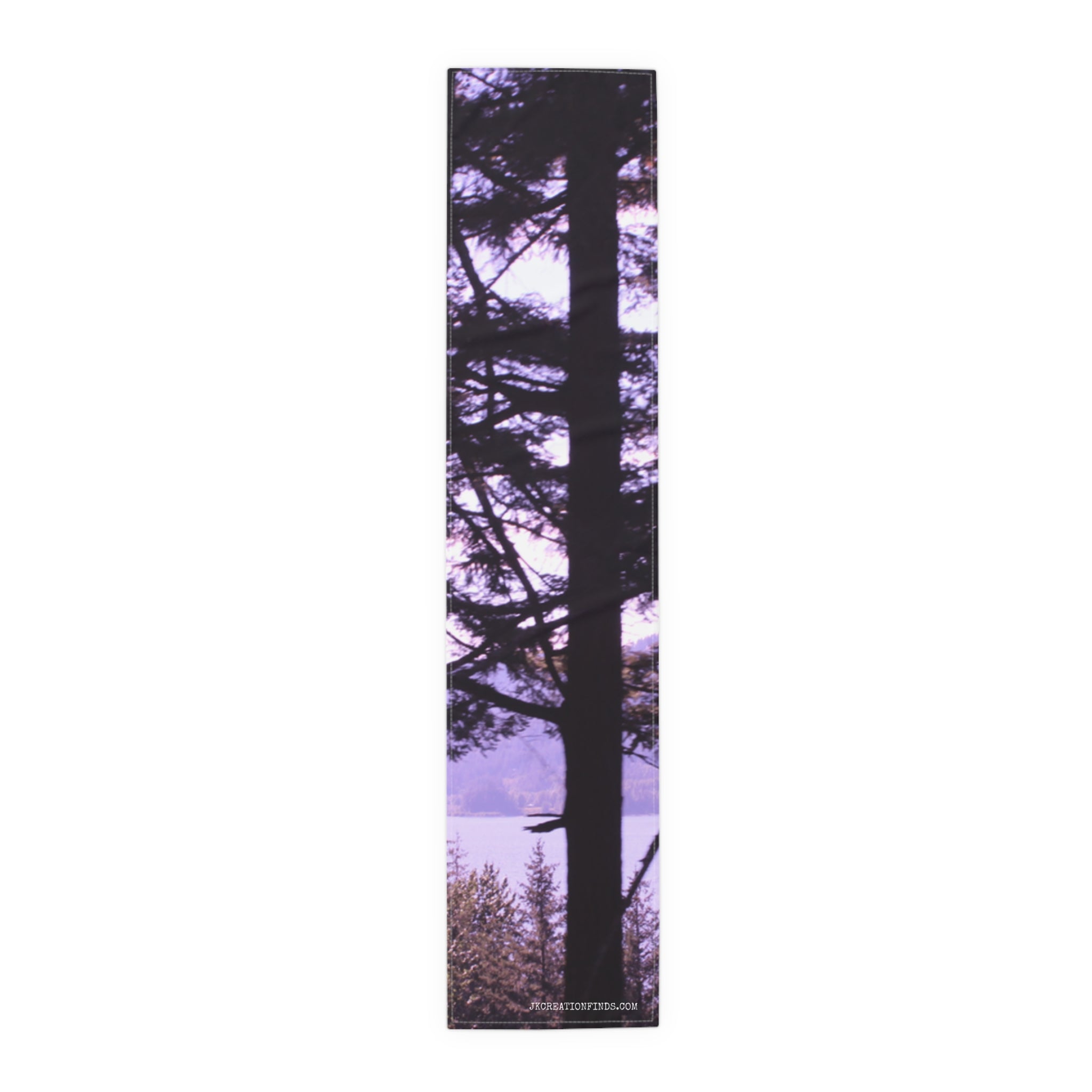 Tall pine tree silhouetted against a purple sky and distant lake.