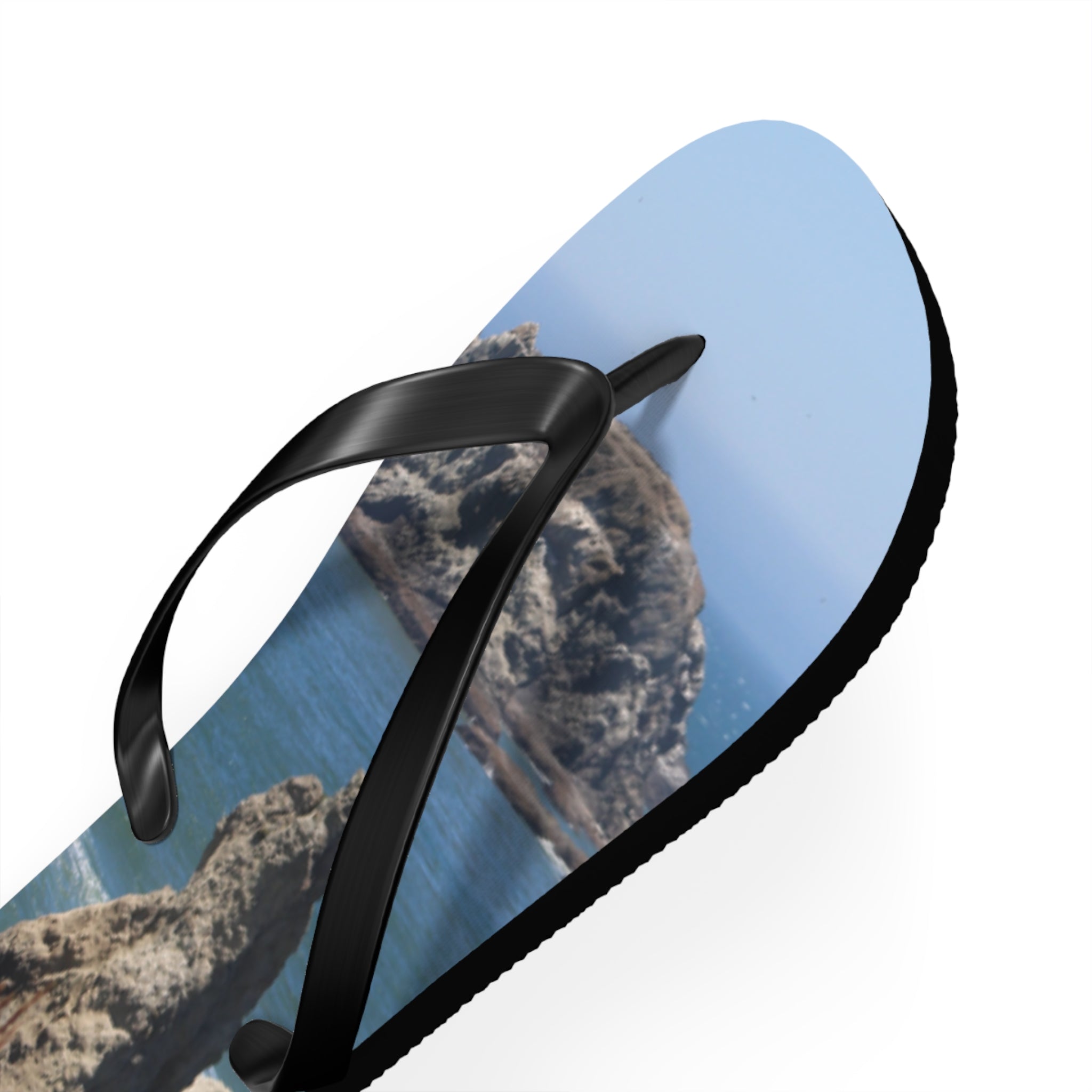 Black flip-flop with a rocky coastal landscape printed on the sole.