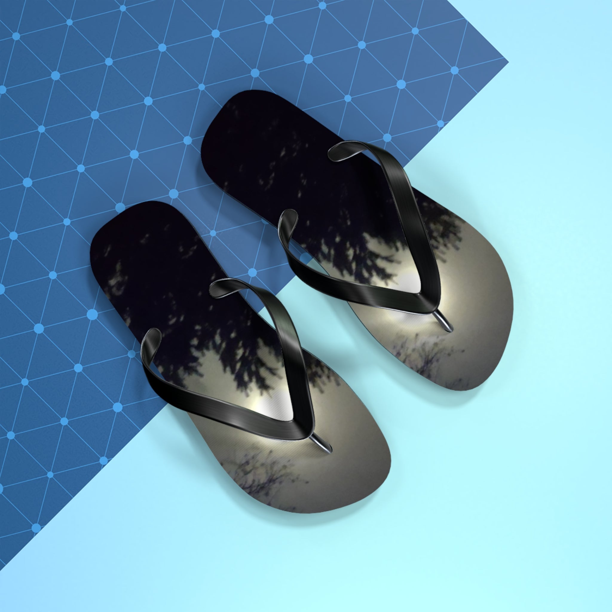 Black flip-flops with a moonlit sky reflection on the soles.