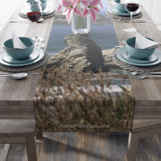Table runner with rocky beach and ocean landscape, with flowers and place settings.