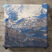 Textured pillow with snowy mountain landscape and pine trees.