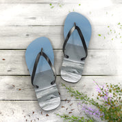 Blue flip-flops with ocean wave design on wooden planks.