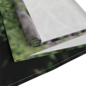 Rolled fabric with floral pattern against a blurred green background.