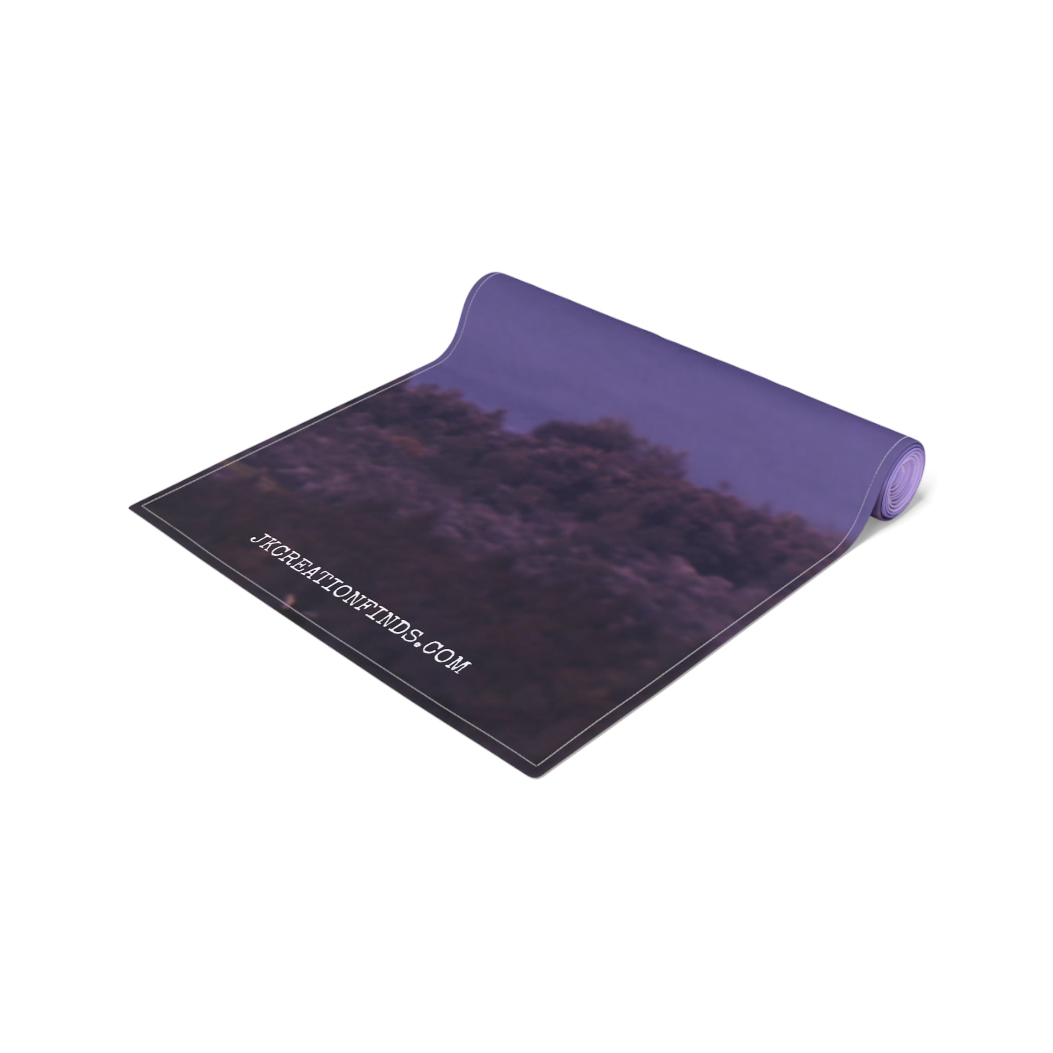 Rolled yoga mat with purple underside and nature scene print.