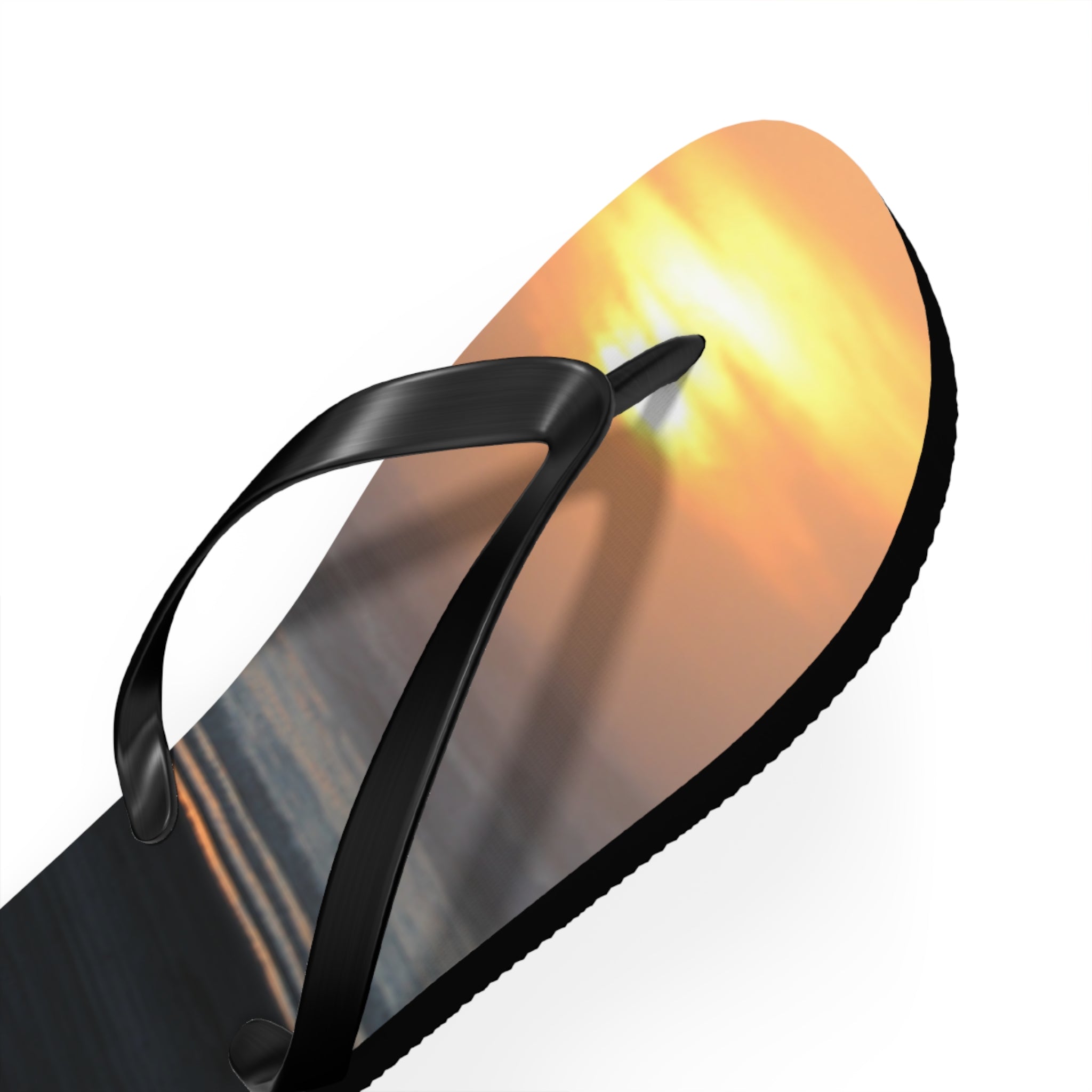 Black flip-flop with sunset on sole against white background.