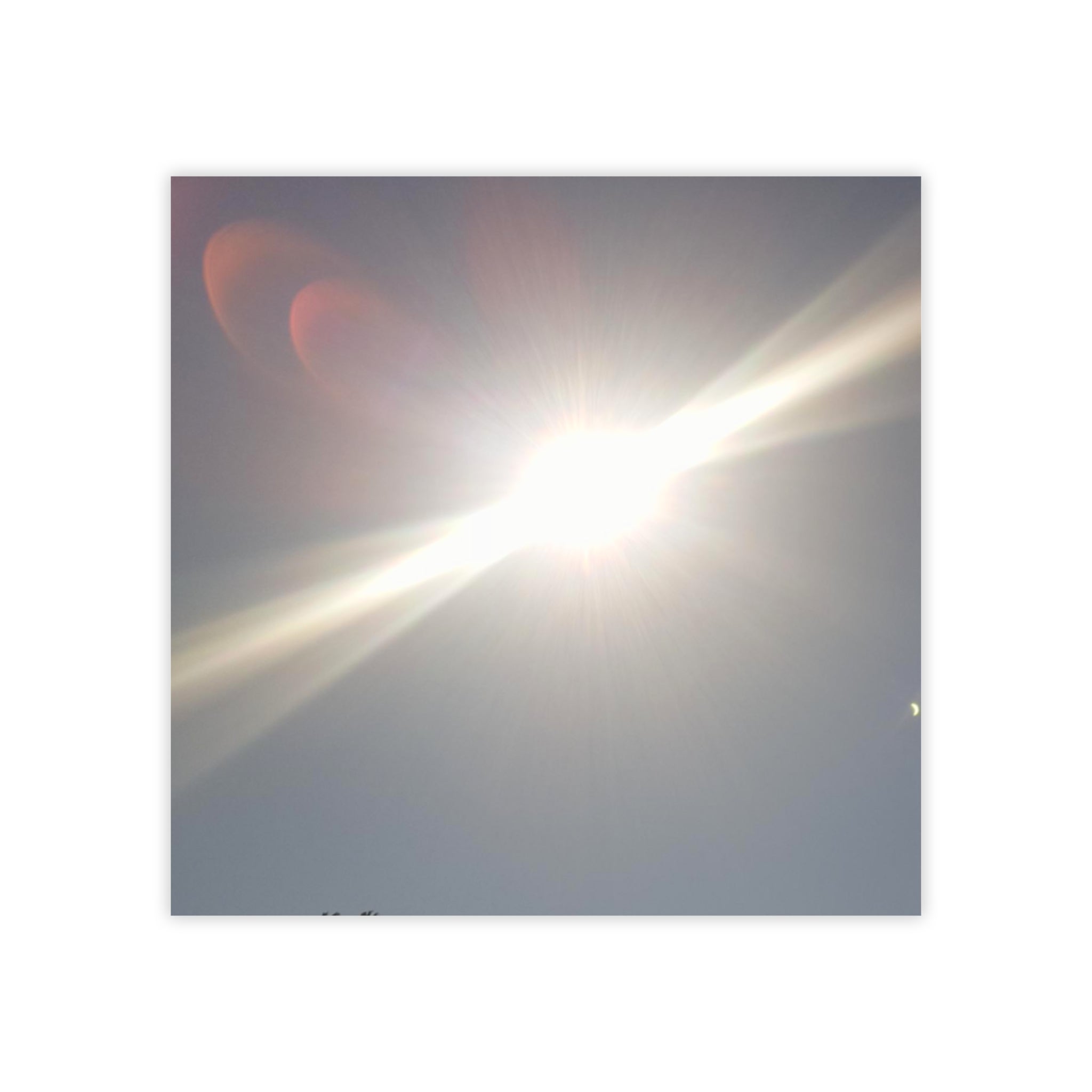 Sun's glare creating a bright lens flare against a hazy sky.