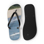 Black flip-flops with a beach and waves graphic on the sole.