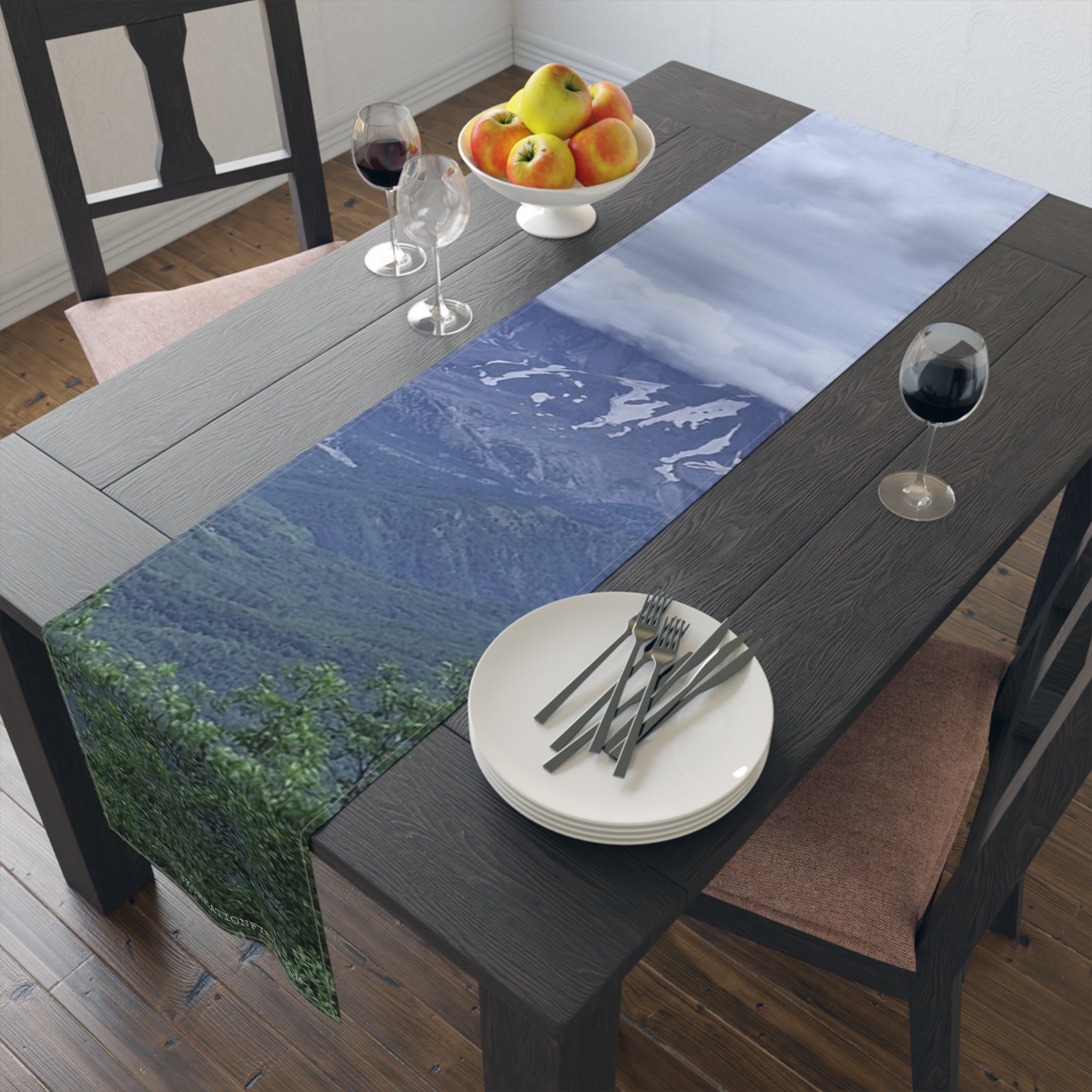 Table runner with mountain landscape and silverware on a dining table.